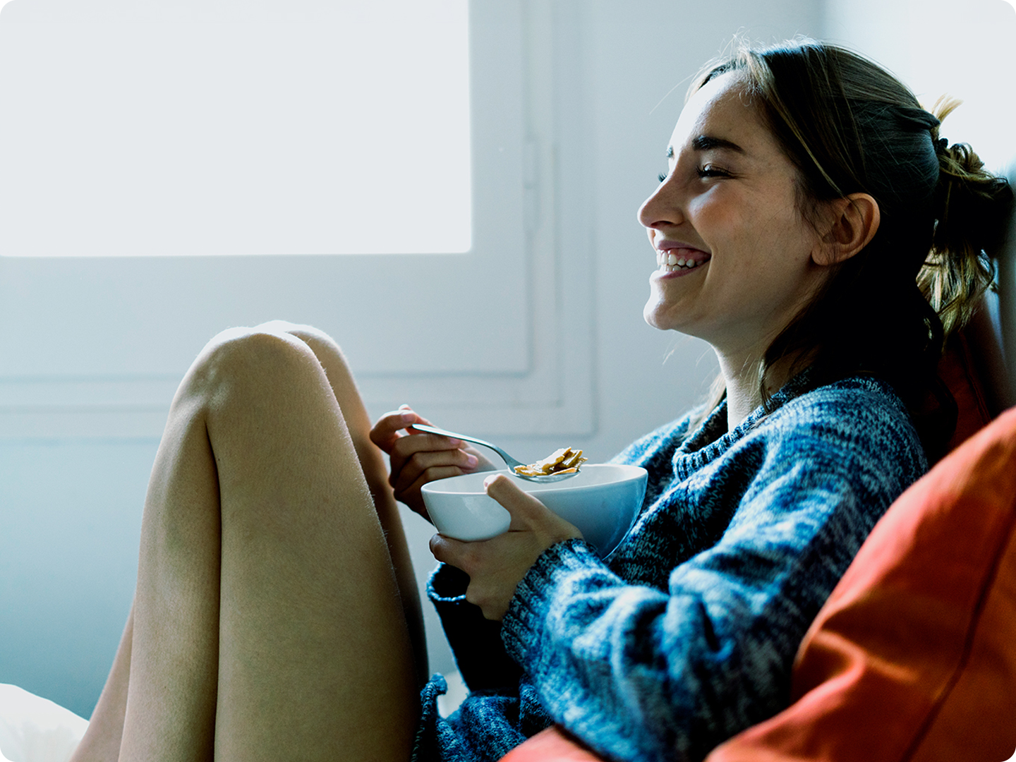 Young woman eats cereal while watching tv.